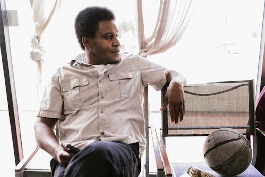 Black Man Sitting on Chair in Barbershop