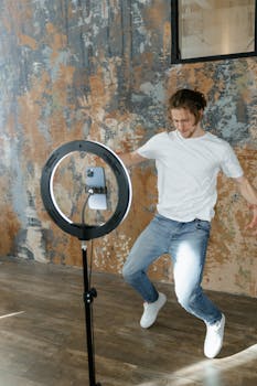 Man in White T-shirt and Blue Denim Jeans Standing Near Round Mirror